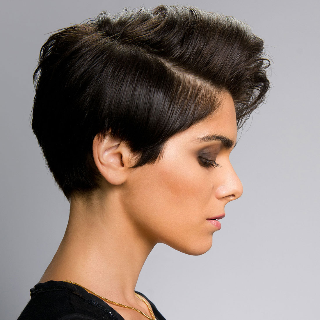 Profielfoto van een fotomodel met kort opgeknipt geknipt donkerbruin zwart haar aan de zijkant en een lok met een zijscheiding.