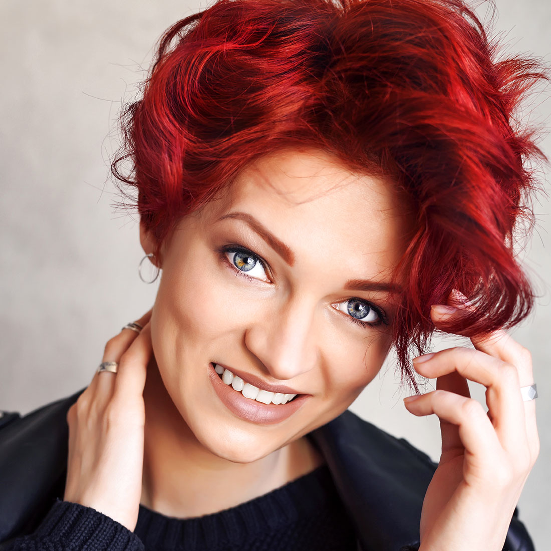 Close-up van spontane vrouw met pittig kapsel van kort haar met slagen en middenscheiding met prachtig rood gekleurd haar.