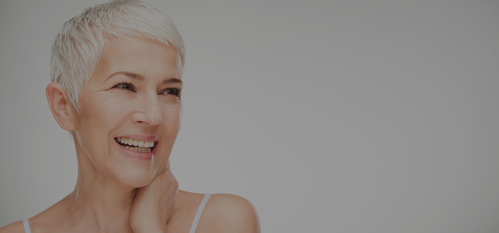 Close-up van vrouw met kort opgeknipt en mooi natuurlijk grijs-wit haar, eindresultaat van de Gracefully Grey behandelingen.