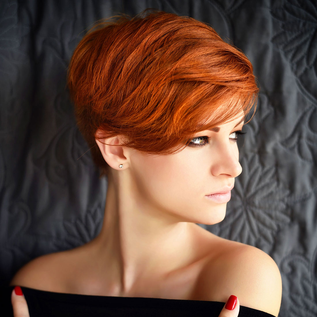 Portret van een mooie jonge vrouw met kort koperkleurig rood haar bovenop asymmetrisch lang.
