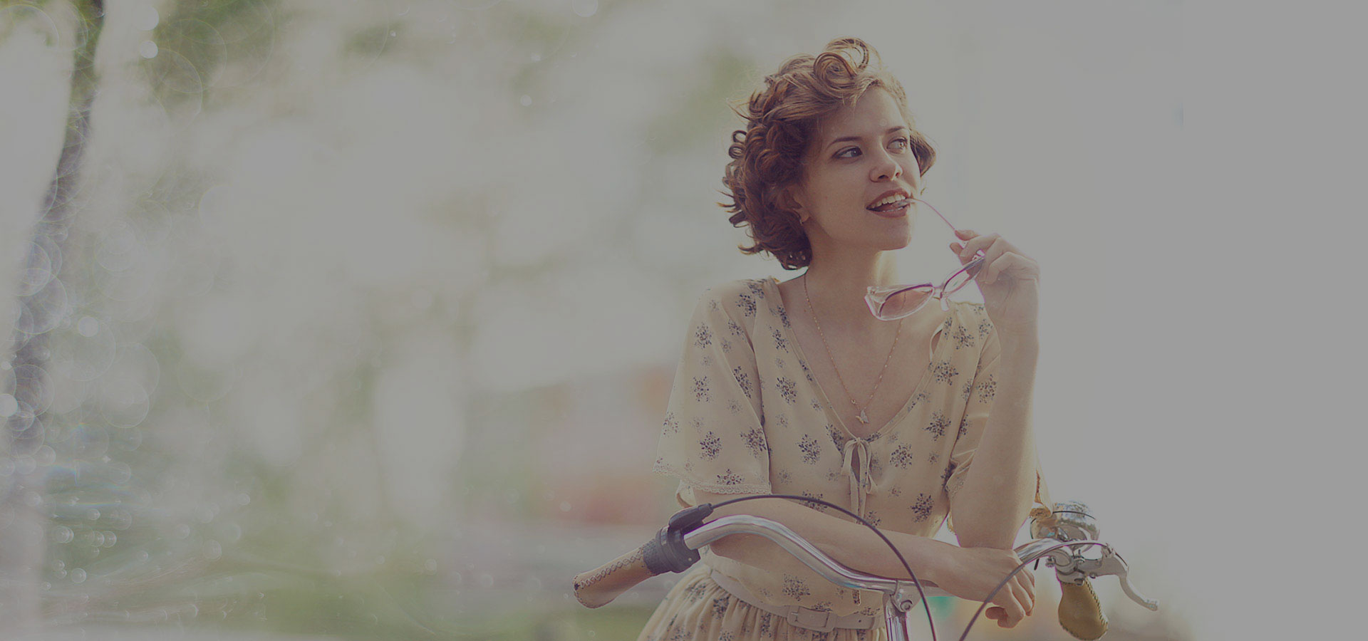 Vrouw met retro & vintage style bobline kapsel van rood-rossig halflang haar in laagjes met losse krullen bij haar fiets.